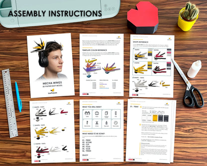 A flat-lay of assembly instructions for a 3D printable mech a wings model, displayed on a wooden desk alongside a 3D printer, ruler, pen, scissors, and other crafting supplies.